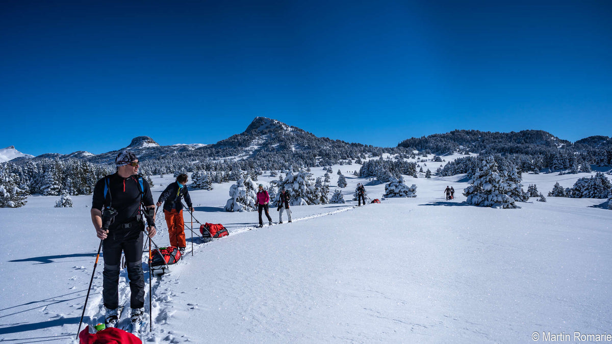 Skieurs nordiques tractant leur pulka sur un plateau enneigé du Vercors