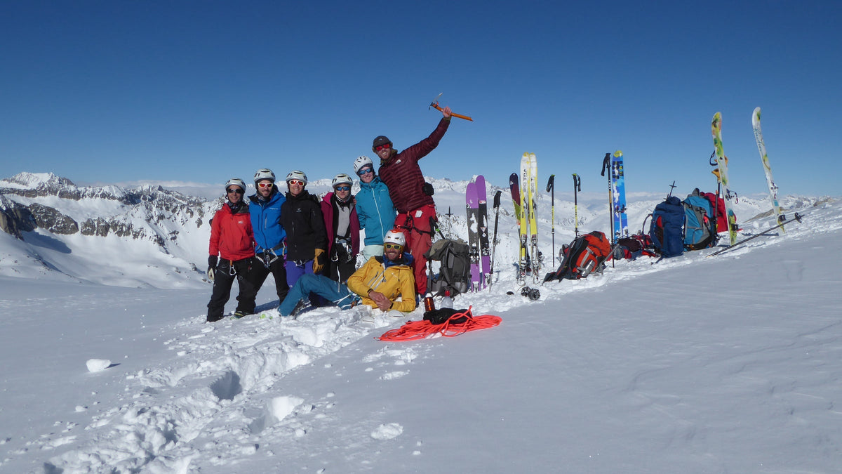 Groupe de skieurs réunis au sommet, skis plantés dans la neige