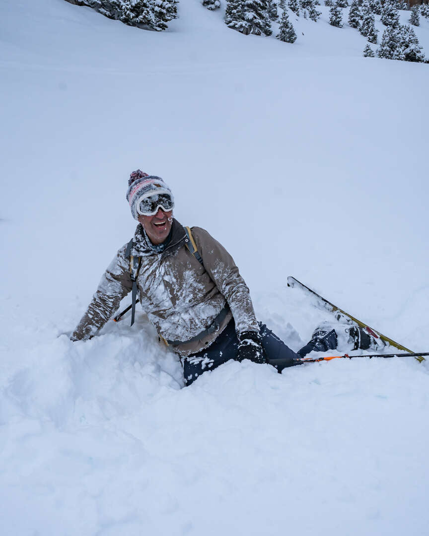 Skieur nordique assis dans la poudreuse après une chute joyeuse