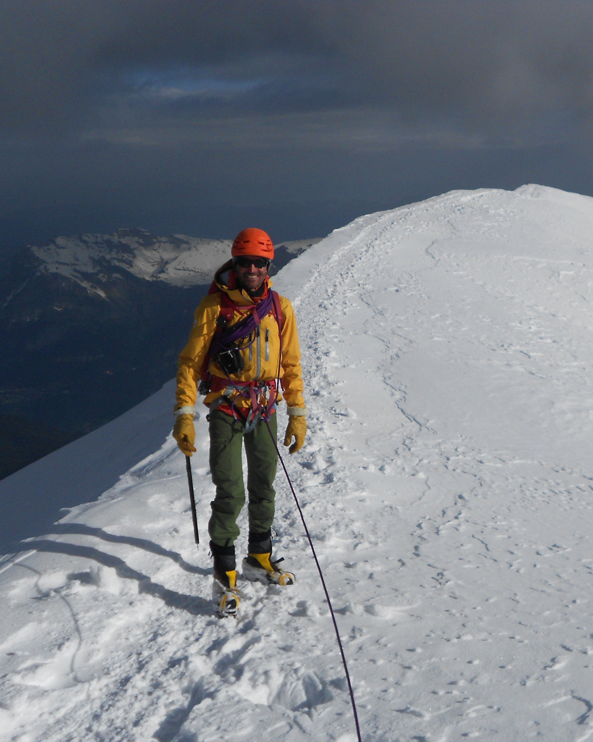 Alpiniste en crampons sur un dôme de neige, piolet à la main