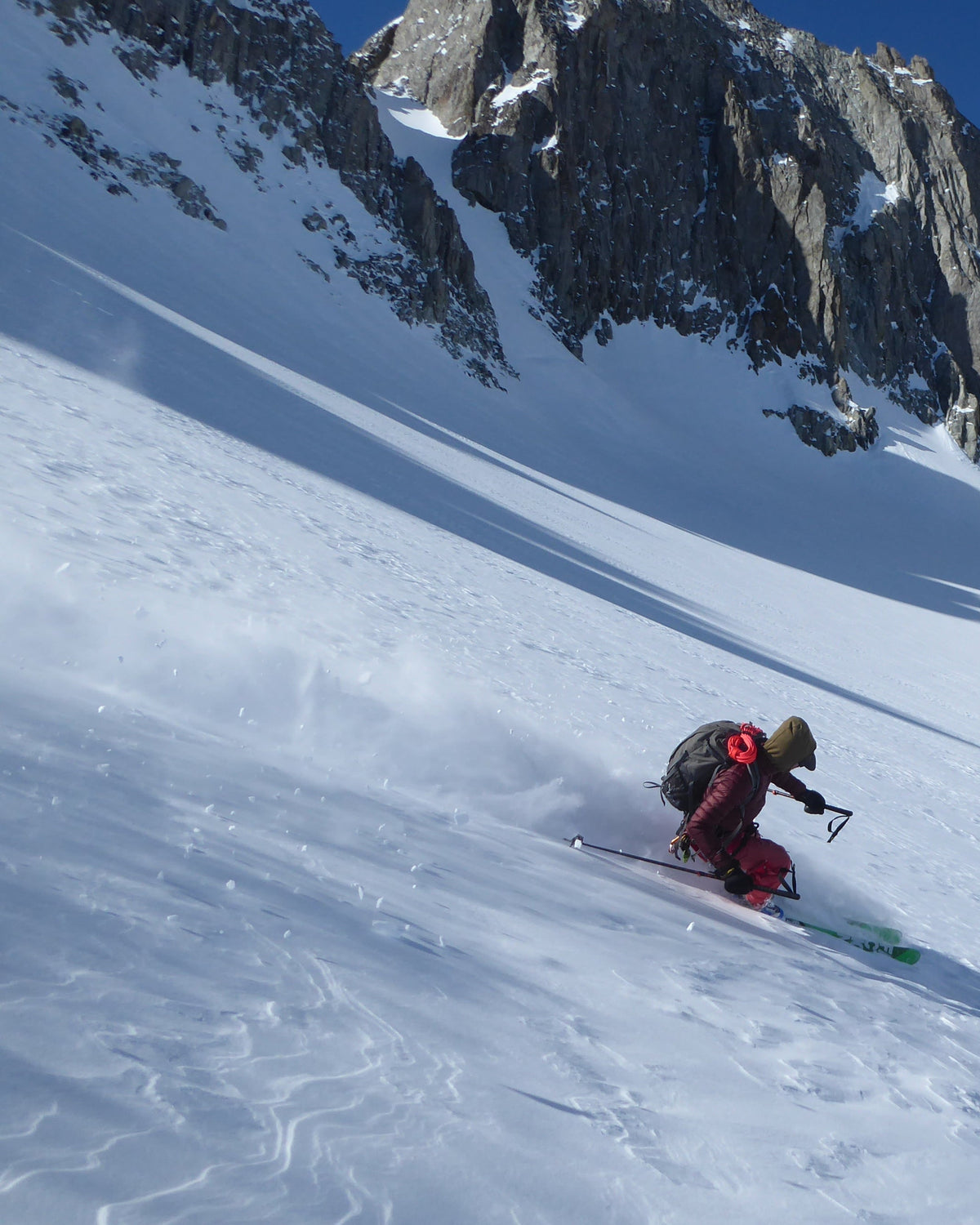 Skieur en pleine descente dans la poudreuse au pied de falaises rocheuses