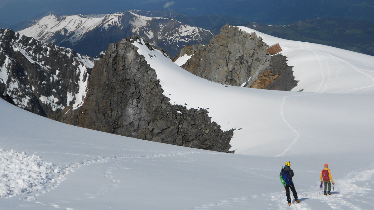 Deux alpinistes encordés sur un glacier enneigé au pied de sommets rocheux