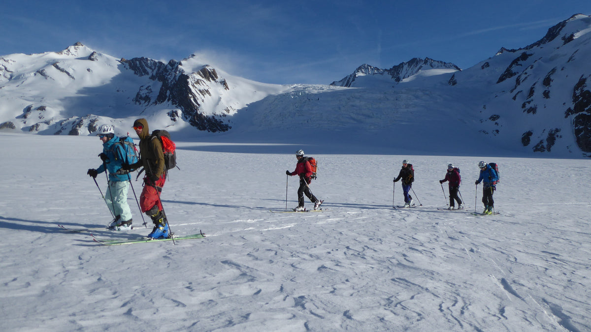 Groupe de skieurs en montée à peaux de phoque sur un plateau enneigé