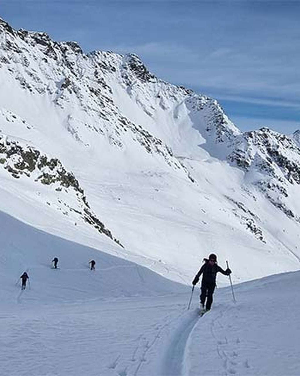 Skieurs de randonnée espacés sur une longue pente de neige
