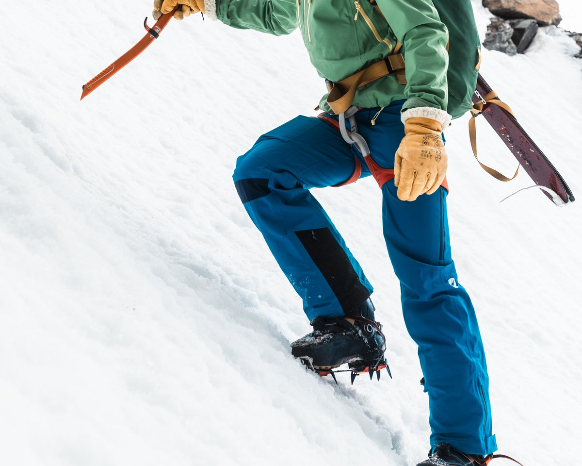 Homme en ski-alpinisme portant le pantalon de ski de rando Lagoped SUPA bleu roi, montée raide au piolet et crampons