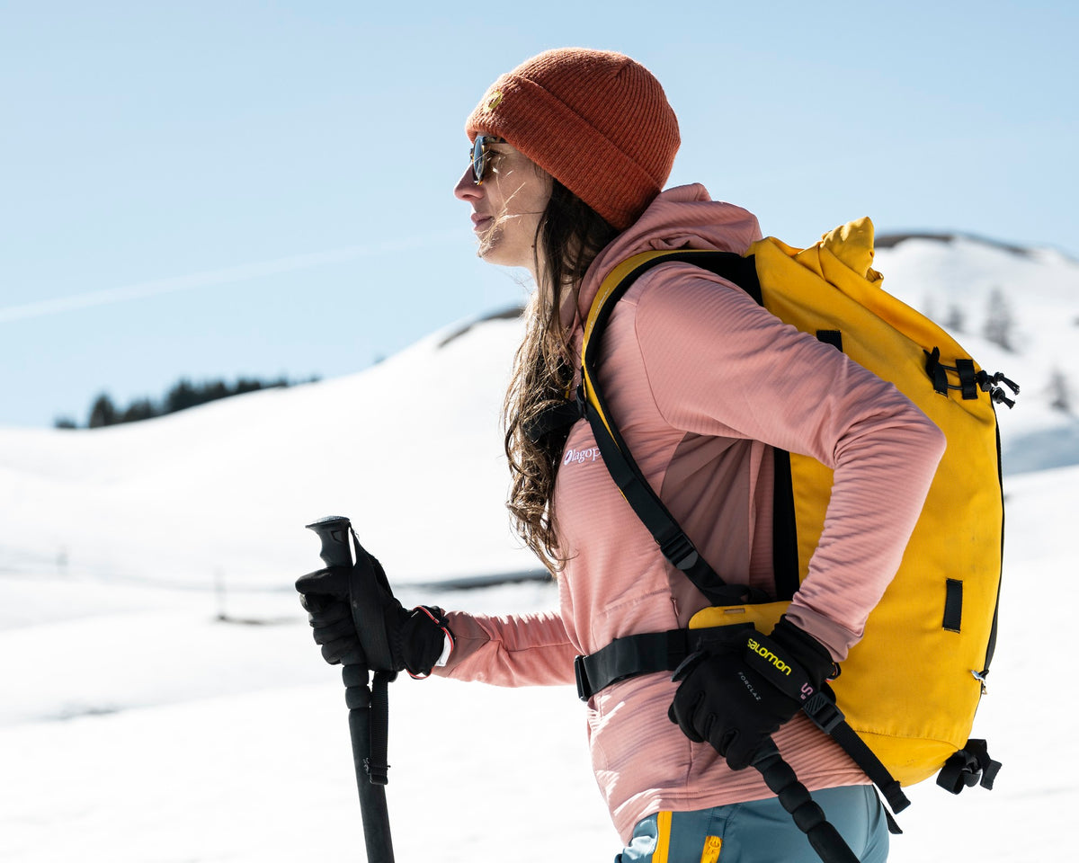 Femme en ski de randonnée portant la polaire technique à capuche Lagoped GELINOTTE HOODIE magnolia, montée en peaux au printemps