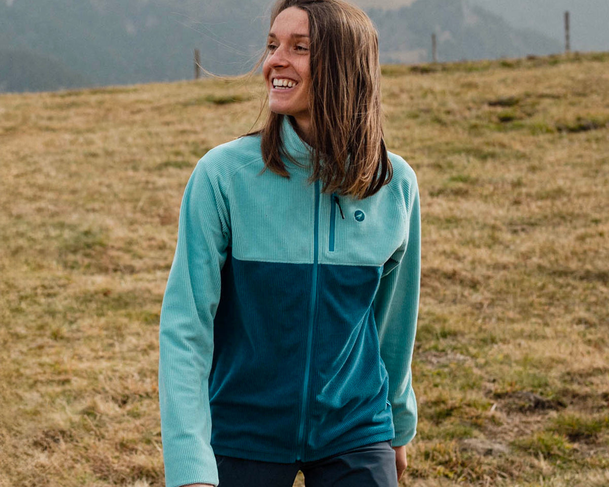 Femme en randonnée portant la polaire technique Lagoped PHANTOM glacier, marche souriante dans un alpage d'automne