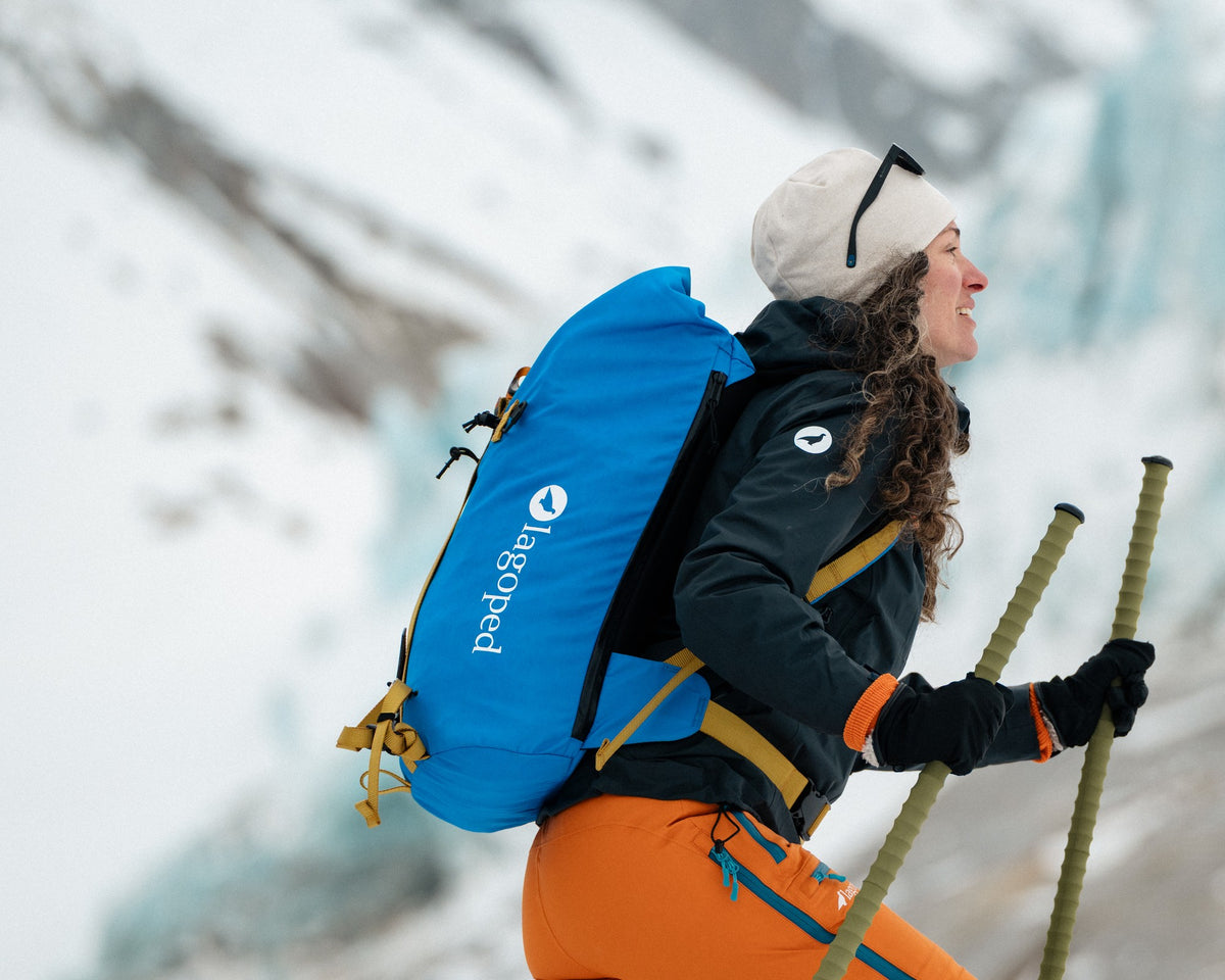 Femme en ski de randonnée portant le sac à dos Lagoped KIIRUNA2 bleu roi, montée bâtons en main au pied des séracs