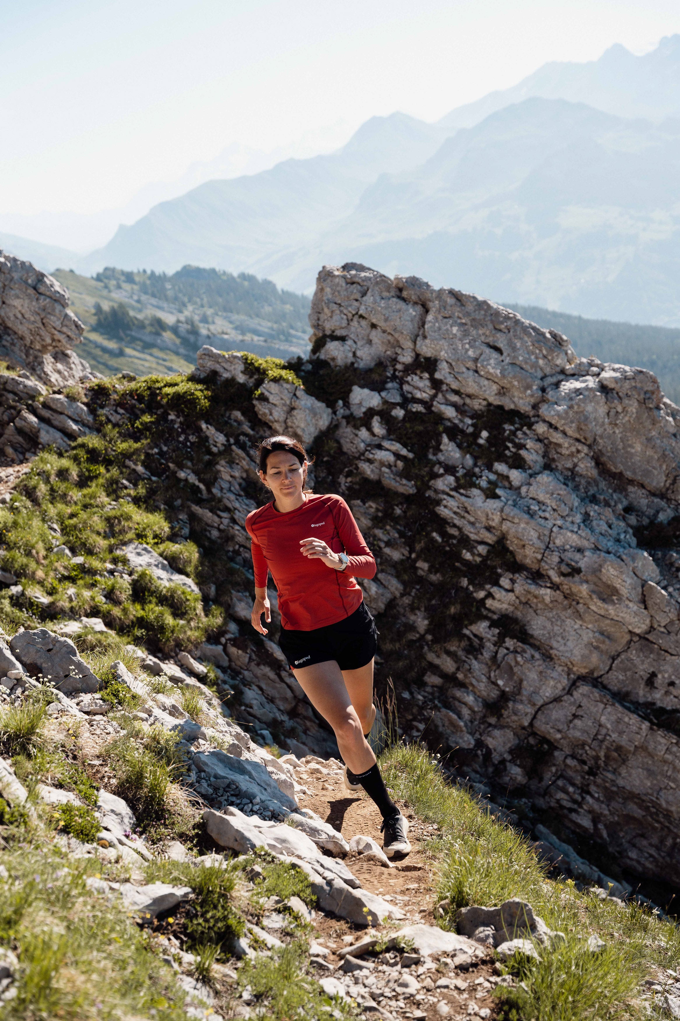 Femme portant un short Lagoped Milvus rouge, trail running en demi-saison en montagne
