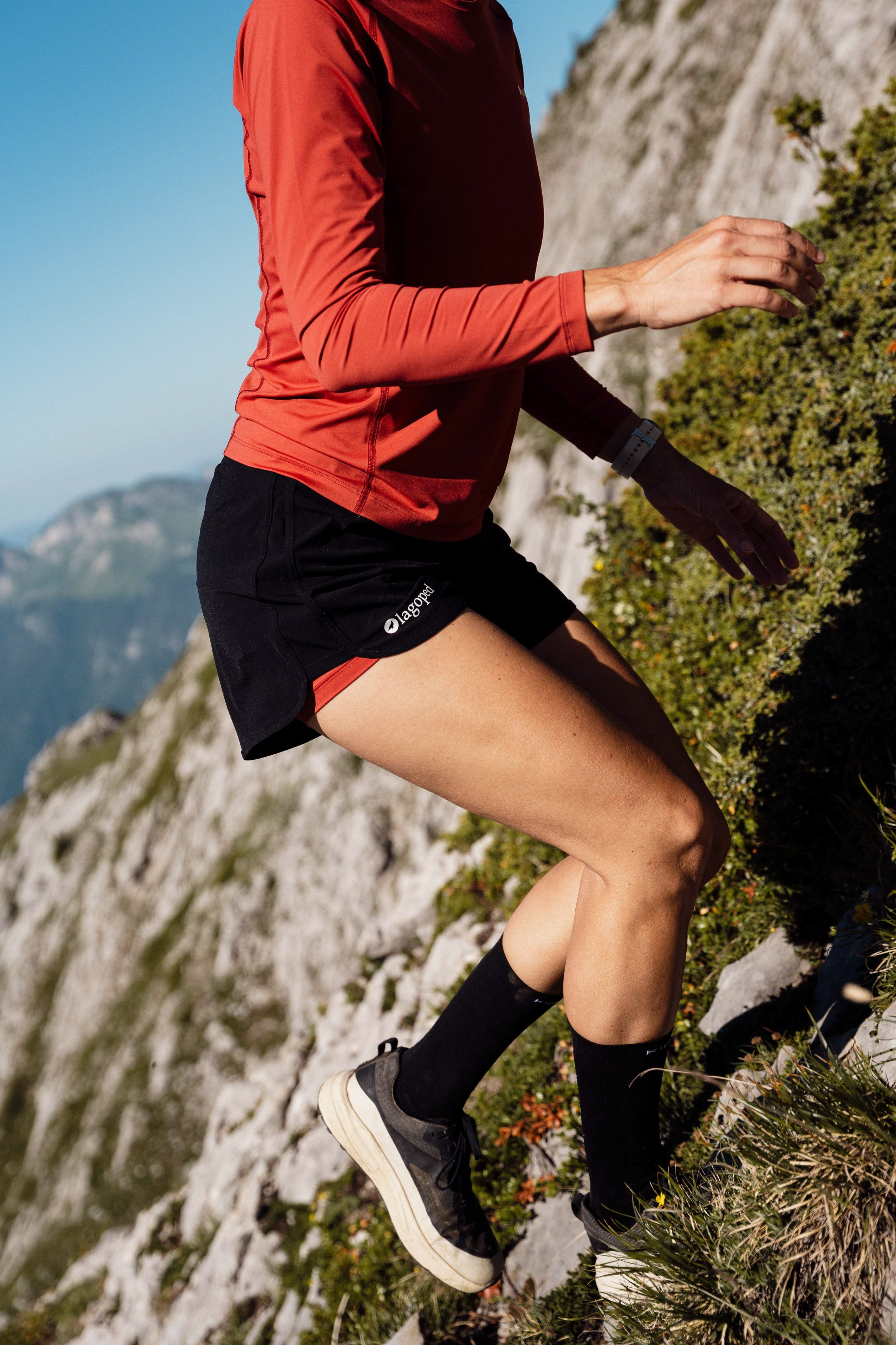 Femme portant un short Lagoped Milvus rouge, course à pied en été en montagne