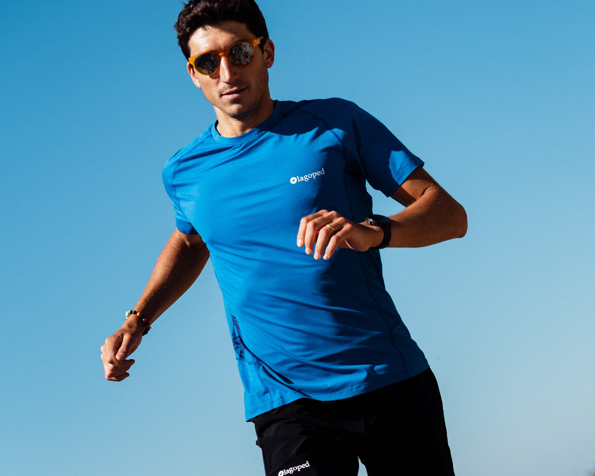 Homme en trail descendant un sentier rocheux en courant, portant le t-shirt technique Lagoped TEETREK bleu roi navy