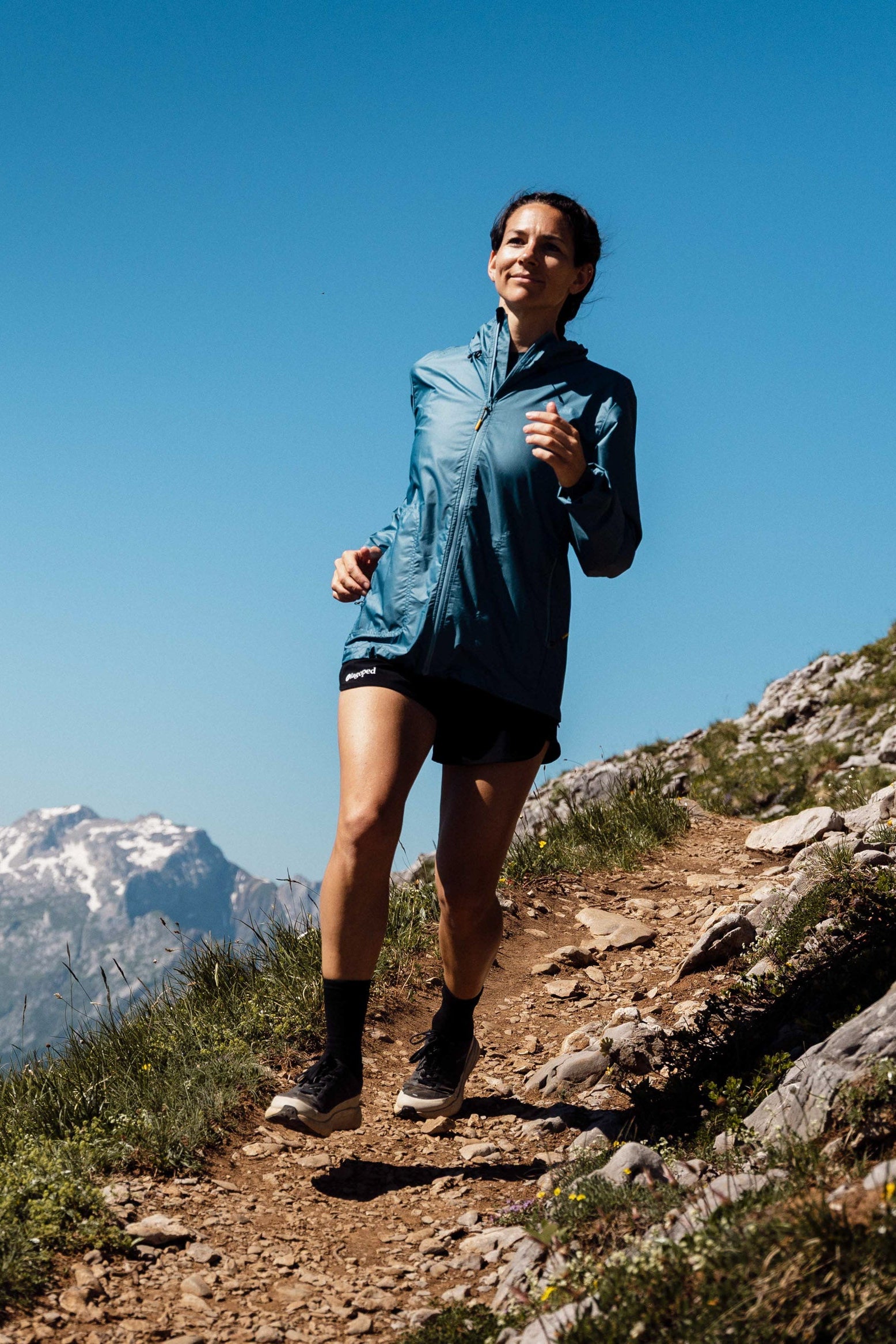 Personne portant un coupe vent Lagoped Nagalaka bleu sarcelle, trail running en demi-saison au sommet