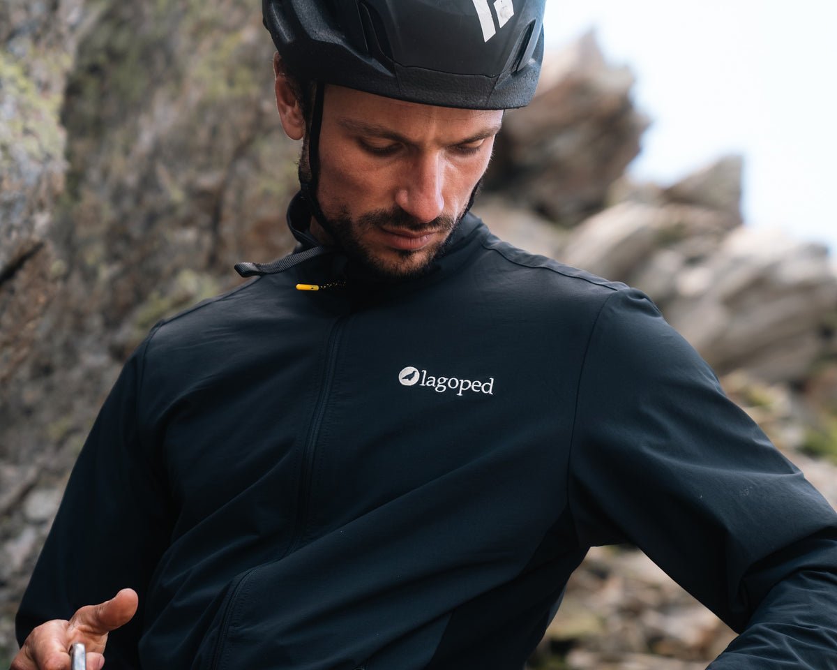 Homme en escalade préparant ses dégaines, portant la veste softshell Lagoped UKPIK bleu indigo, en été